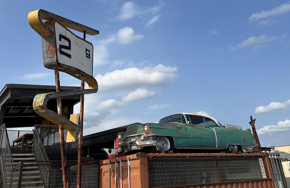 Mitten in einem lustlosen Gewerbegebiet hat er ein PS-Paradies gebaut, zu dem neben der Werkstatt und der privaten Autosammlung zumindest bis vor Corona auch noch eine Kneipe und ein Souvenirshop gehört.