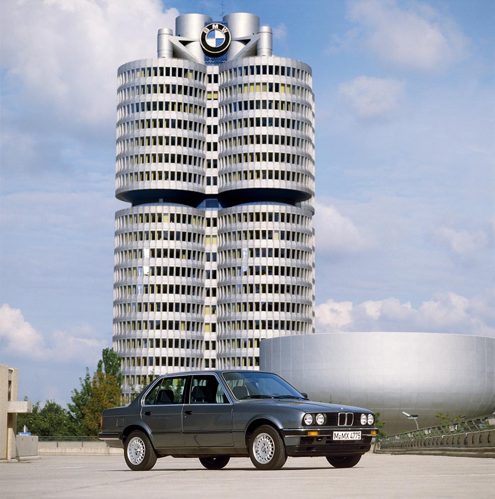 BMW 3er E30 viertuerige Limousine ab 1983 vor BMW Museum rechts (ab 1973) und Vierzylinder Unternehmenszentrale (ab 1972).