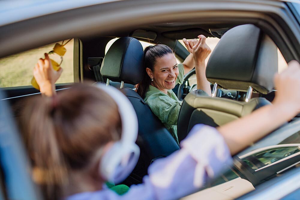 Young mother and little daughter having fun in their electric car.