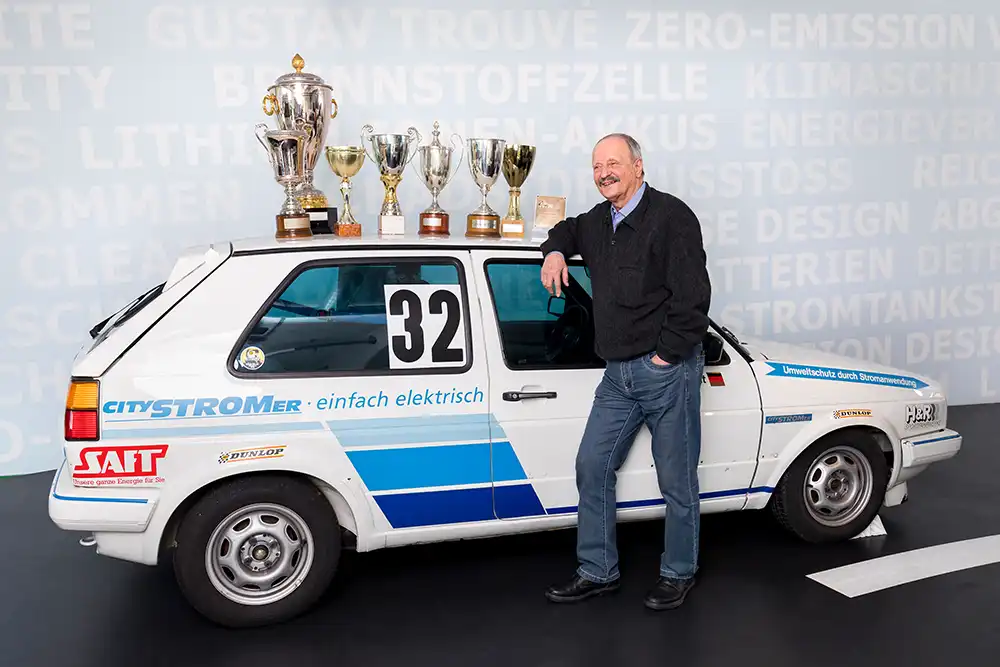 1985: Die zweite Generation des vollelektrischen Golf CityStromer debütiert, dies als Dreisitzer mit Elektromotor. Neben dem CityStromer posiert der Rennfahrer Hagen Arlt.