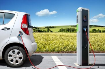 Elektroauto E-Car an Ladestation vor Landschaft. Symbolbild. Foto stock.adobe.com