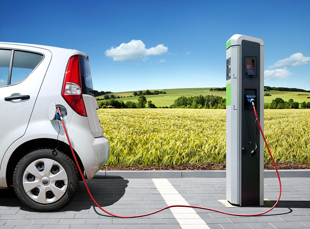 Symbolbild. Elektroauto E-Car an Ladestation vor Landschaft. Foto: Petair - stock.adobe.com