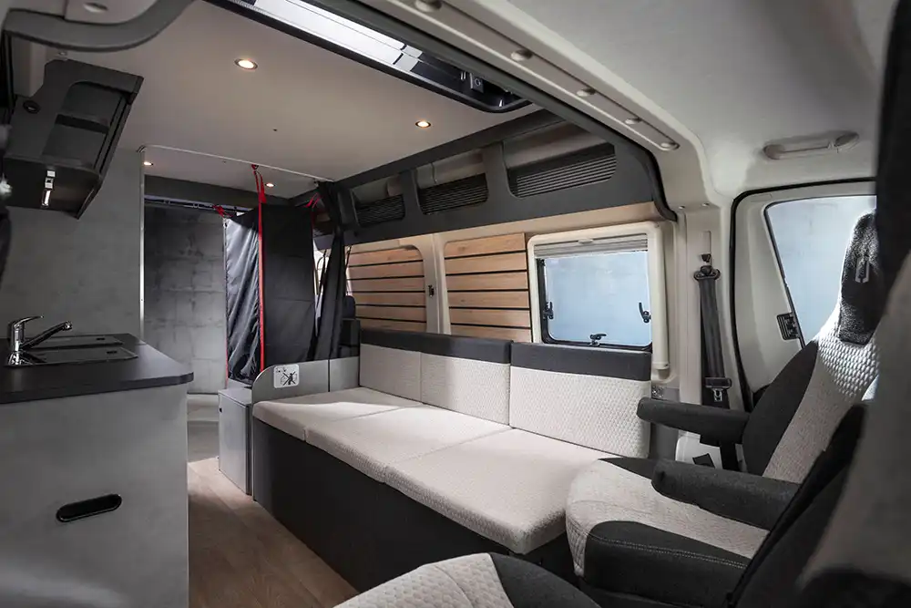 In der Fahrzeugmitte ist auf der Fahrerseite ein längs angeordnetes Sofa angeschlagen, das sich nachts zu einer Schlafstätte für zwei Personen mit einer Liegefläche von 188 mal 133 Zentimeter ausklappen lässt. Foto: Crosscamp