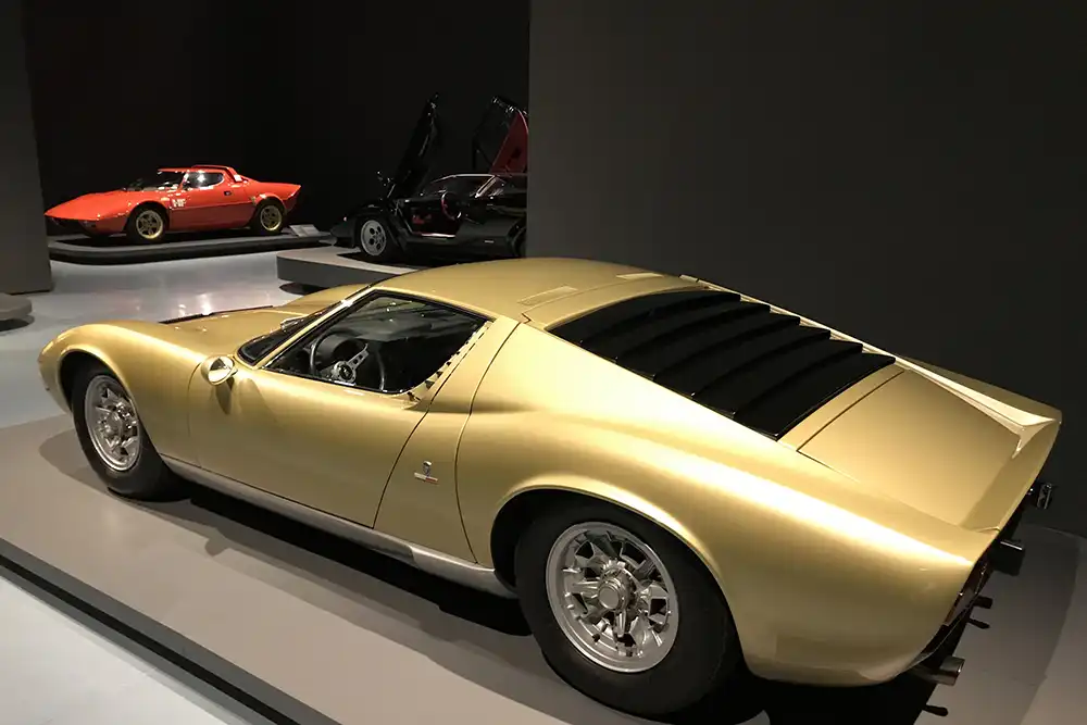 Die Seitenlinie des Lamborghini Miura zeigt die extrem flache Silhouette und die markante schwarze Lamellenabdeckung über dem V12-Mittelmotor.
