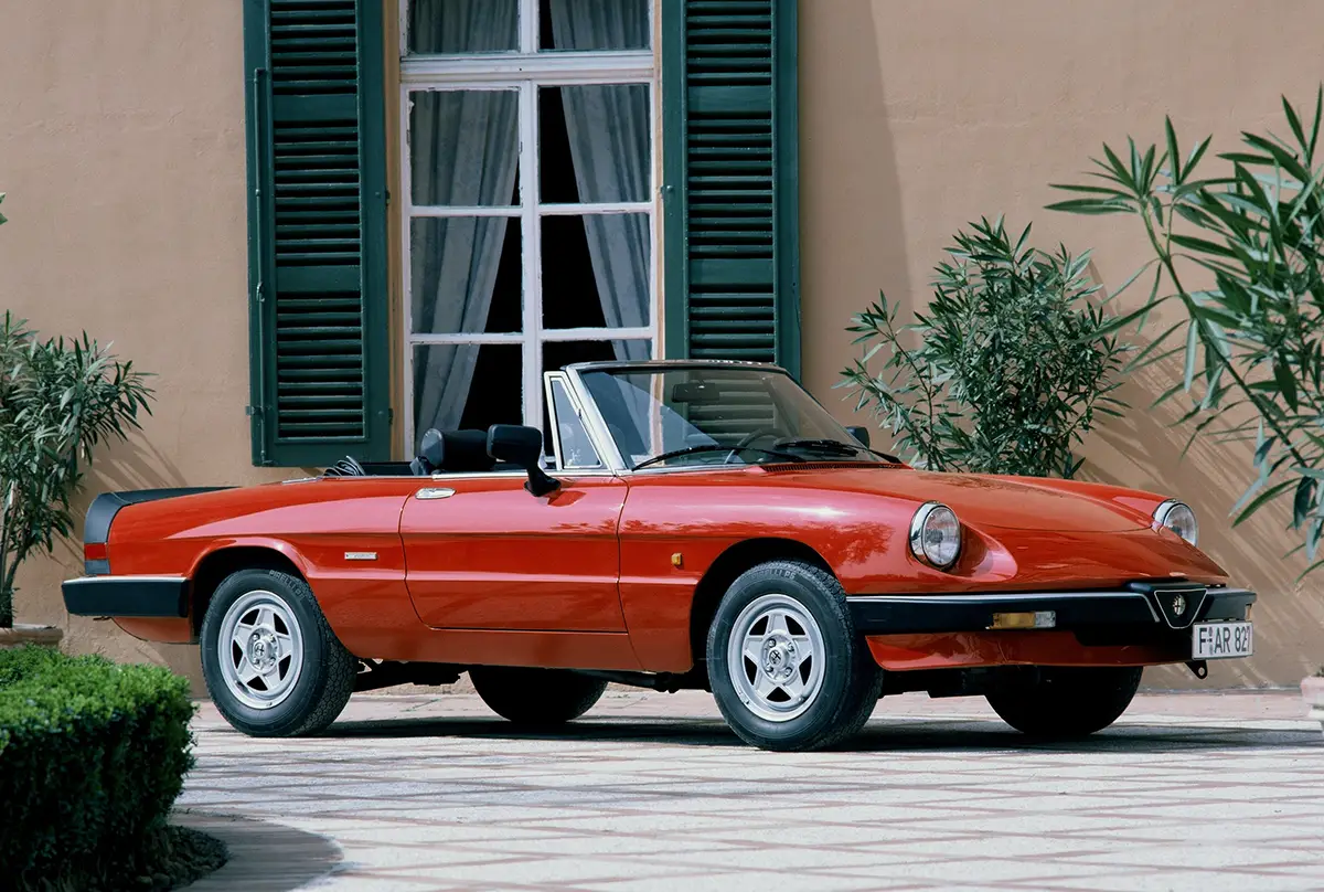 Roter Alfa Romeo Spider Aerodinamica der dritten Serie mit Gummispoilern vor einer eleganten Villa.