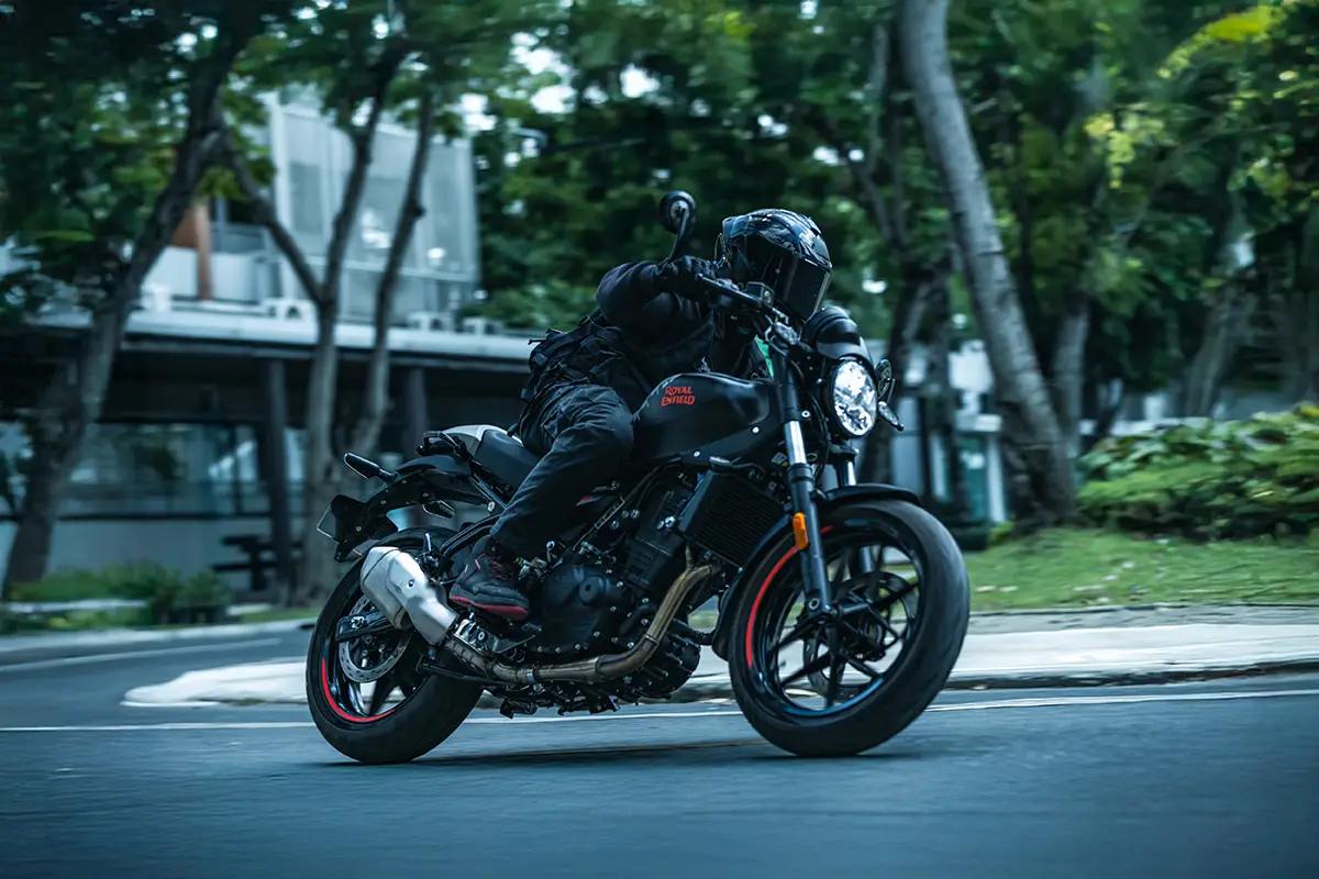 Die neue Royal Enfield Guerrilla 450 Apex in dynamischer Schräglage auf einer Landstraße – deutlich erkennbar ist die sportlich-tiefere Lenkerposition.