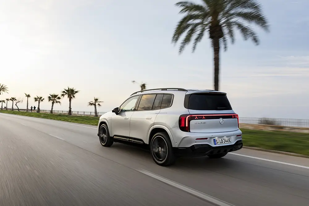 Heckansicht des neuen Mercedes GLB mit markanten LED-Rückleuchten während der Fahrt auf einer Küstenstrasse.