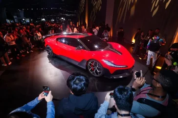 Die feuerrote Nebula Next 01 Concept Jet Edition bei der Weltpremiere in San Francisco, präsentiert auf einer Bühne vor Publikum und Medienvertretern.