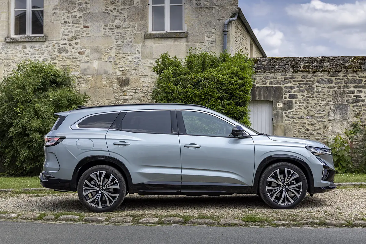 Seitenprofil der 4,75 Meter langen Karosserie des Renault Espace E-Tech 200 SUV vor einer historischen Steinfassade.