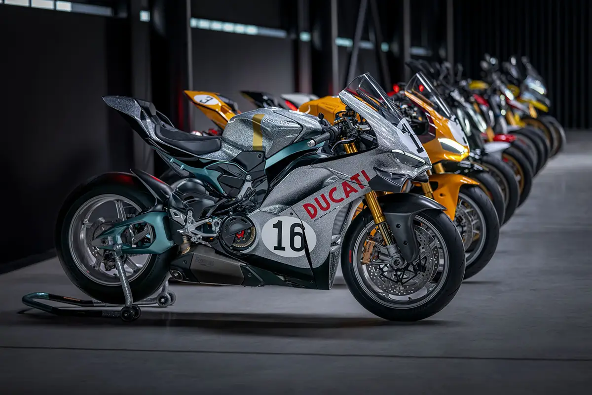 Nahaufnahme eines limitierten Ducati Panigale V4 S Supersportlers im klassischen silber-roten Rennsport-Design mit der Startnummer 16, gefolgt von weiteren auf 100 Stück limitierten Jubiläumsmodellen.