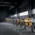 Line of sport motorcycles lined up in a dim showroom, with helmets displayed on racks in the background.