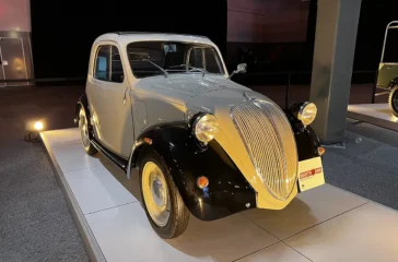 Historischer Ur-Fiat 500 Topolino von 1936 in zweifarbiger Lackierung mit schwarzen Kotflügeln und der markanten Fahrzeugfront im Werk Turin-Lingotto.