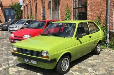 Hellgrüner Ford Fiesta der ersten Generation (1976) vor einem historischen Backsteingebäude.
