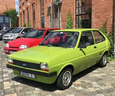 Hellgrüner Ford Fiesta der ersten Generation (1976) vor einem historischen Backsteingebäude.
