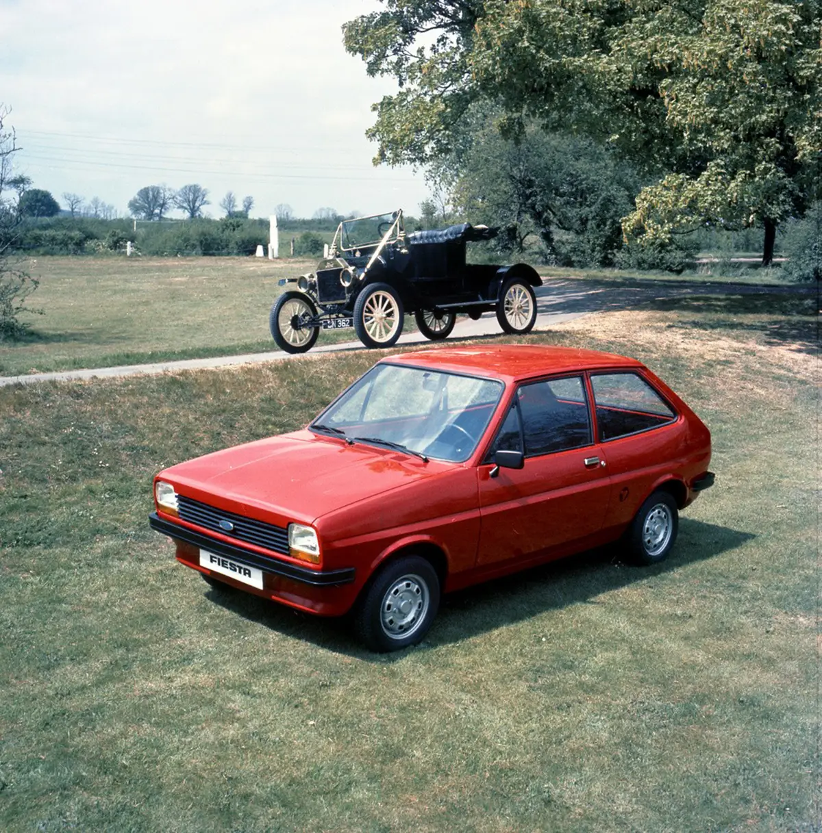 Roter Ford Fiesta I im Vordergrund vor einem historischen Ford Modell T als Symbol für die wichtigste Neuentwicklung seit 1908.