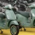 Die beiden Sondermodelle der Vespa 80th Anniversary Edition – eine GTS 310 und eine Primavera 125 – nebeneinander präsentiert in der exklusiven pastellgrünen Lackierung.