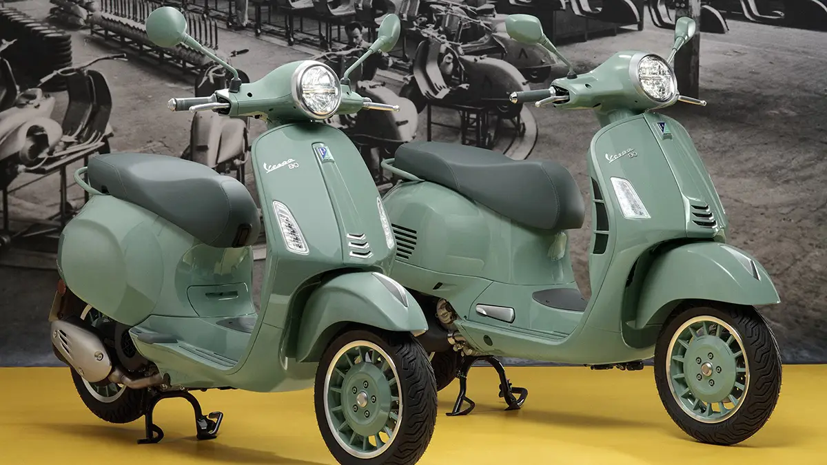 Die beiden Sondermodelle der Vespa 80th Anniversary Edition – eine GTS 310 und eine Primavera 125 – nebeneinander präsentiert in der exklusiven pastellgrünen Lackierung.