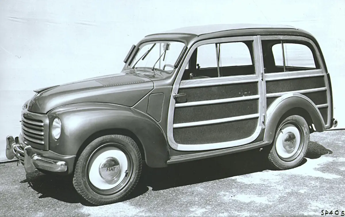 Historischer Kombi Fiat 500 Topolino Giardiniera in Grau mit den typischen „Woodie“-Holzverkleidungen an den Seiten aus den 1950er-Jahren.