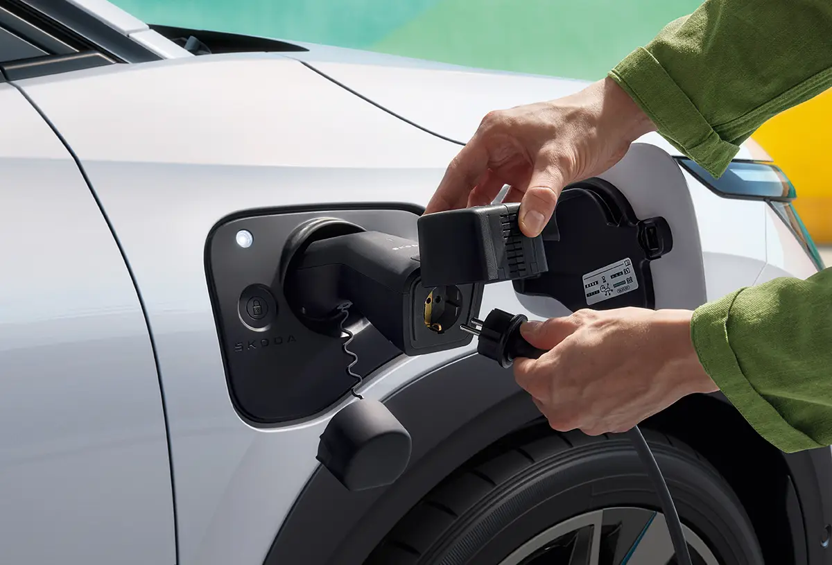 Nahaufnahme des Ladevorgangs an der vorderen Seitenwand des Skoda Epiq zur Demonstration der Ladeinfrastruktur.