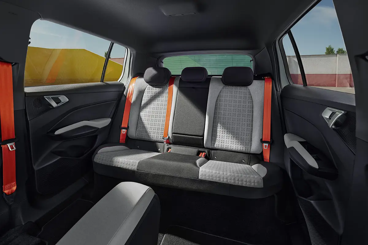 Die großzügige hintere Sitzbank des Skoda Epiq aus nachhaltigen, recycelten Materialien mit kontrastierenden orangefarbenen Sicherheitsgurten.