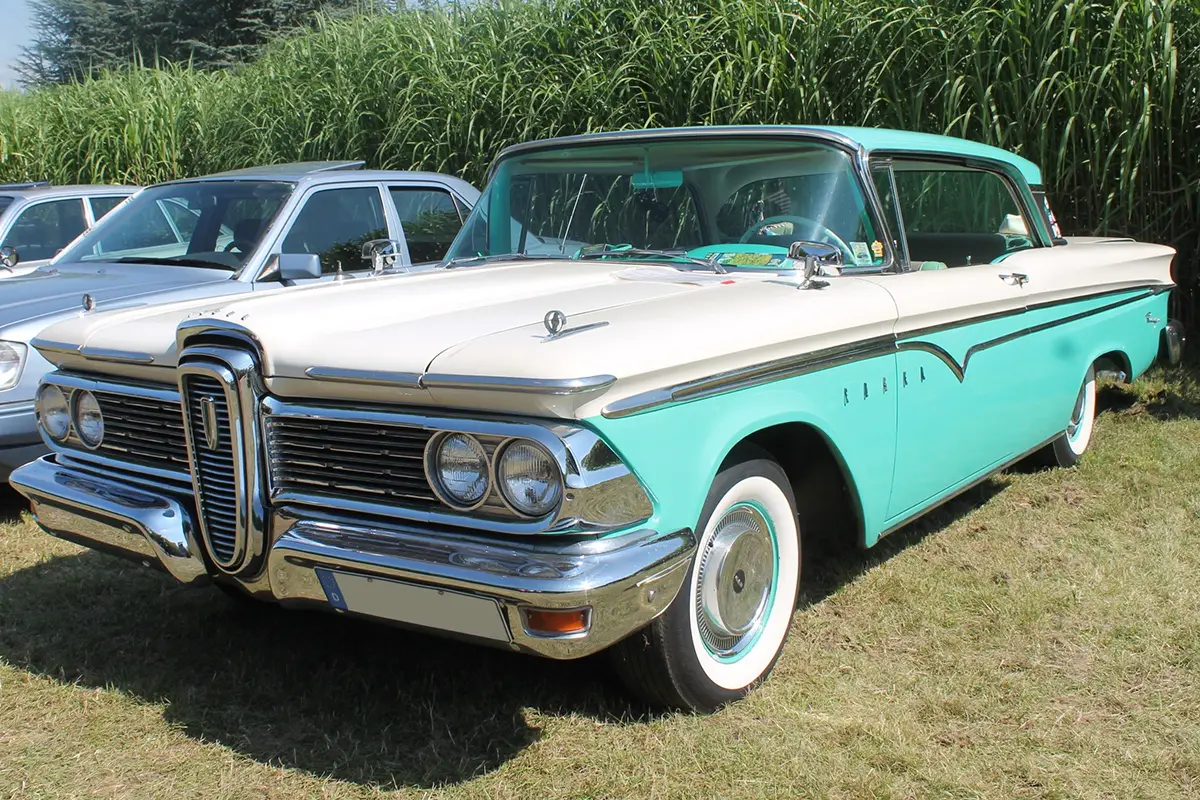 Ein historischer Ford Edsel in Weiß und Helltürkis, dessen markanter vertikaler Kühlergrill Ende der 1950er Jahre zum Synonym für ein automobiles Design-Debakel wurde.
