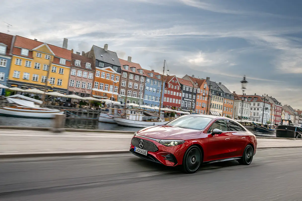 Der Mercedes CLA in roter Lackierung vor einer urbanen Kulisse, der nun auch mit Verbrennungsmotor angeboten wird.