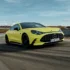 Ein gelbes Mercedes-AMG GT 4-Türer Coupé in der Frontansicht bei einer dynamischen Fahrt auf dem Asphalt einer Rennstrecke.