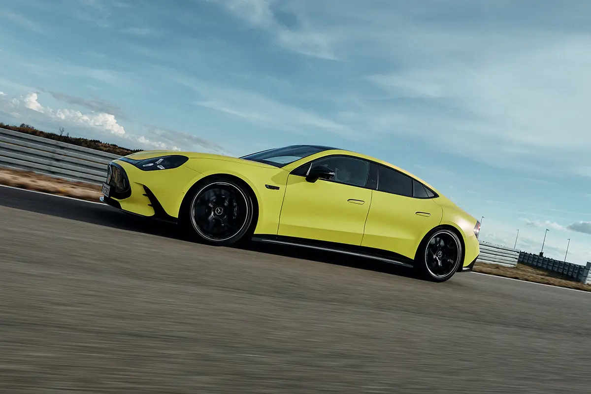 Die flache Seitenlinie des gelben Mercedes-AMG GT 4-Türer Coupés zur Demonstration der aerodynamischen Karosserieproportionen auf einer Teststrecke.
