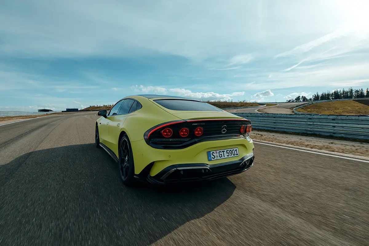 Das gelbe Mercedes-AMG GT Elektro-Coupé aus der Heckperspektive mit Fokus auf die sportlichen Rückleuchten während der Fahrt auf einer Rundstrecke.