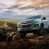 Der überarbeitete Isuzu D-Max Pick-up bei einer Offroad-Fahrt im unwegsamen, felsigen Gelände vor einer weiten Landschaftskulisse unter bewölktem Himmel.