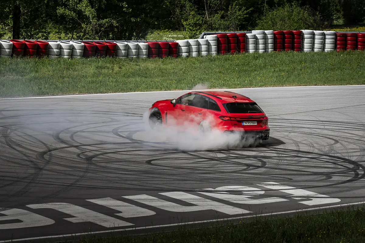 Ein roter Audi RS 5 beim kontrollierten Donut-Drift im sportlichsten Fahrmodus auf der nassen Fahrbahn eines Handlingkurses.