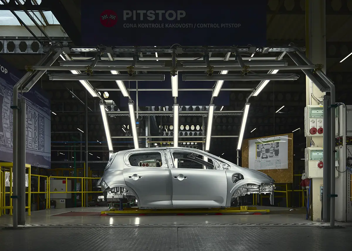 Ein silberner Renault Twingo E-Tech Electric in einer modernen, hell ausgeleuchteten Kontrollstation mit dem Schild „Pitstop“ zur optischen Überprüfung der Oberflächenqualität.