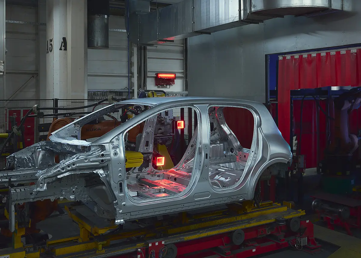 Eine nackte, silberne Twingo-Fahrzeugkarosserie im Rohbau auf dem Fließband während der Montage im Werk.
