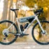 Das neue Canyon Grizl AL Gravel-Bike in Silber-Grau mit montierter Rahmentasche, zwei Trinkflaschen und einem Frontgepäckträger, perfekt in Szene gesetzt in einem herbstlichen Waldgebiet.