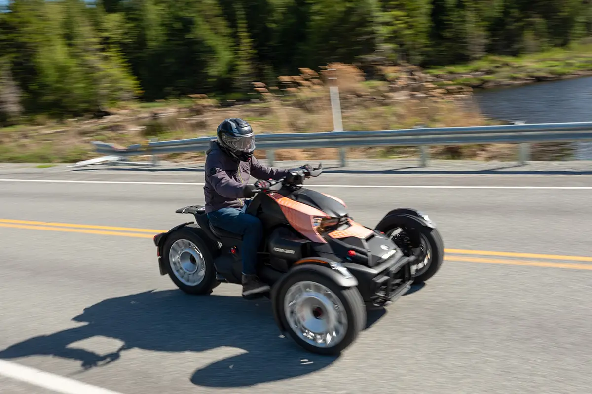 Dynamische Seitenansicht des Can-Am Ryker Rally in voller Fahrt, die die tiefe Sitzposition des Fahrers und die aggressive Fahrhaltung verdeutlicht.