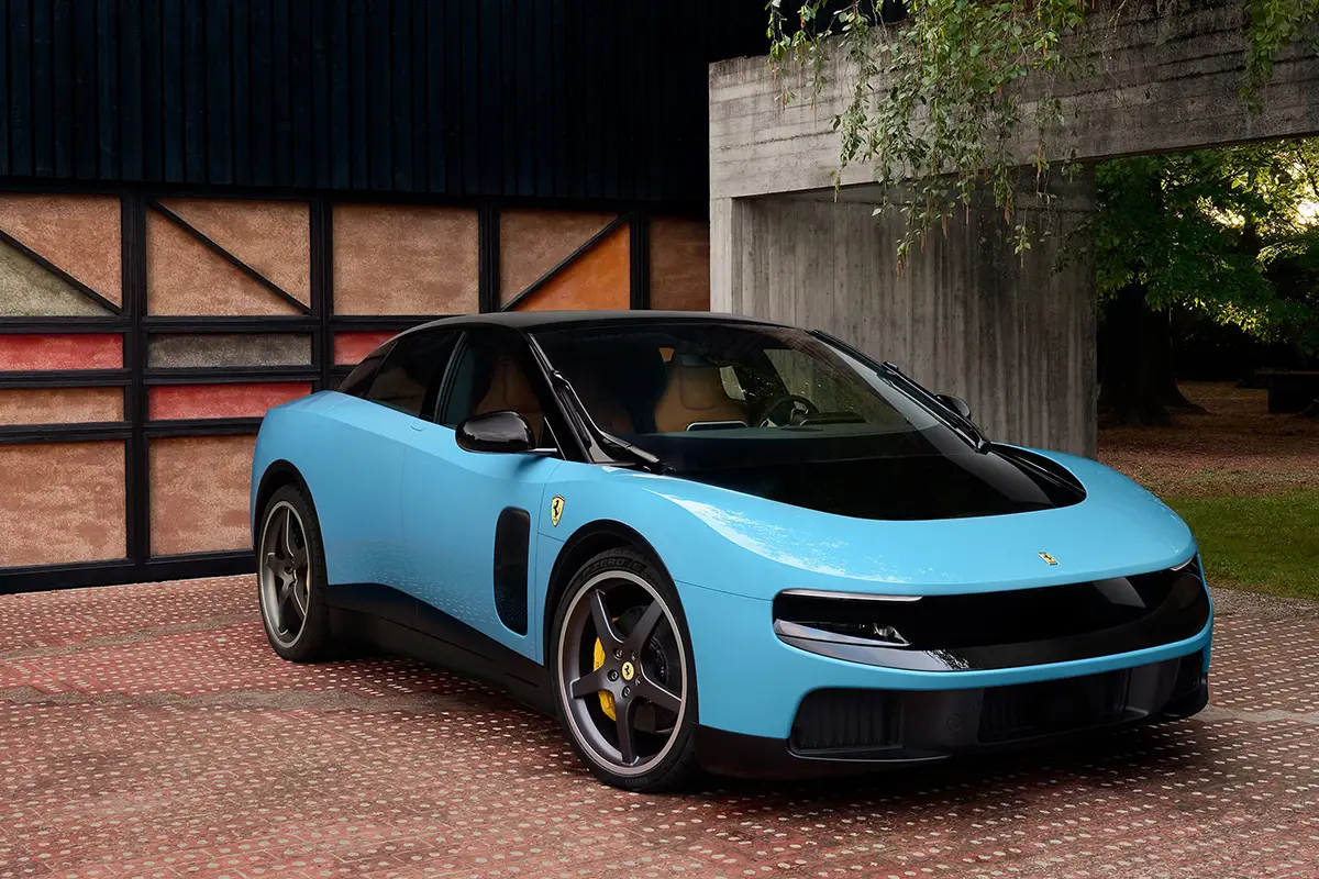Die Frontalansicht des Ferrari Luce in einer eleganten hellblauen Lackierung, geparkt vor einem modernen Wohngebäude mit Garagentor.