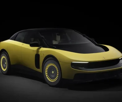 Dreiviertel-Frontansicht des neuen Ferrari Luce in sportlichem Gelb-Gold mit abgedunkeltem Glasdach und aerodynamischen Felgeneinsätzen vor dunklem Hintergrund.