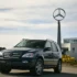 Ein klassischer, dunkler Mercedes-Benz ML vor dem Hauptgebäude von Mercedes-Benz US International in Tuscaloosa mit dem großen, hoch aufragenden Mercedes-Stern im Hintergrund.