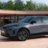 Die schräge Frontansicht des neuen Lancia Gamma Crossover-Modells in Grau, das durch prägnante Lichtsignaturen und große, aerodynamisch gestaltete Alufelgen besticht.
