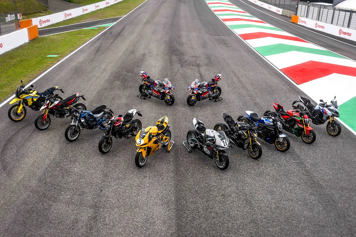 Luftaufnahme von zehn exklusiven Ducati Motorrädern der limitierten Sonderedition Collezione 100, die in einer V-Formation auf dem Asphalt einer Kurve auf der Rennstrecke stehen.
