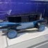 Ein historisches, blaues Modell des Rumpler Tropfenwagens aus den 1920er-Jahren, dessen stromlinienförmige Karosserie exakt der aerodynamischen Form eines fallenden Wassertropfens nachempfunden ist.
