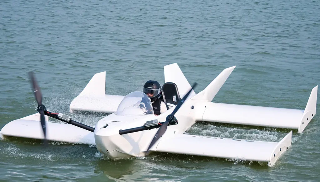 Das weiße, aus Carbon gefertigte Bodeneffektfahrzeug Navee WaveFly 5X mit zwei großen elektrischen Bug-Rotoren gleitet bei einem Testflug knapp über der Wasseroberfläche.