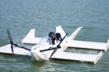 Das weiße, aus Carbon gefertigte Bodeneffektfahrzeug Navee WaveFly 5X mit zwei großen elektrischen Bug-Rotoren gleitet bei einem Testflug knapp über der Wasseroberfläche.