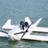 Das weiße, aus Carbon gefertigte Bodeneffektfahrzeug Navee WaveFly 5X mit zwei großen elektrischen Bug-Rotoren gleitet bei einem Testflug knapp über der Wasseroberfläche.