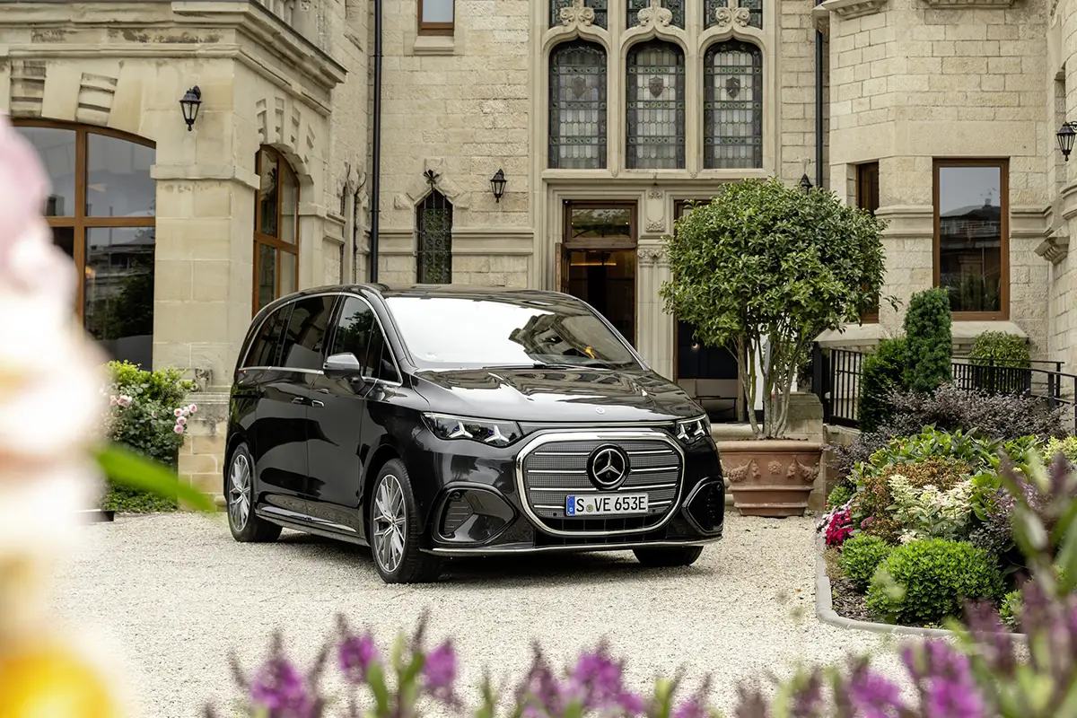 Der Mercedes-Benz VLE in edlem Schwarz parkt elegant auf dem Vorplatz eines historischen, herrschaftlichen Steingebäudes.