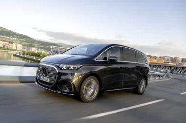 Dynamische Schrägansicht von vorne auf die dunkelblaue Mercedes-Benz VLE Luxus-Großraumlimousine während einer Testfahrt auf einer kurvenreichen Küstenstraße bei Bilbao.