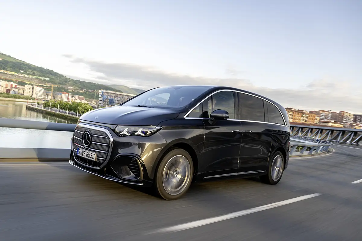 Dynamische Schrägansicht von vorne auf die dunkelblaue Mercedes-Benz VLE Luxus-Großraumlimousine während einer Testfahrt auf einer kurvenreichen Küstenstraße bei Bilbao.