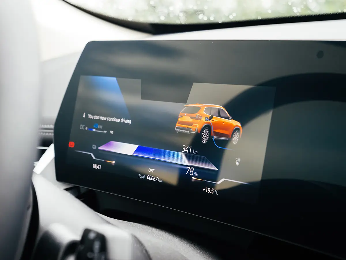 Ein neues Elektroauto von BMW wird aufgeladen; auf dem Armaturenbrett werden eine Reichweite von 667 Kilometern und eine Außentemperatur von 19,5 Grad Celsius angezeigt. Foto: ifeelstock - stock.adobe.com