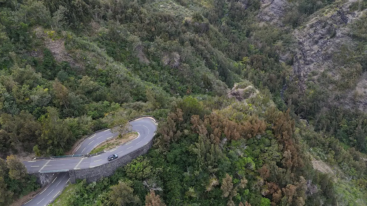 Drohnenaufnahme der extrem kurvenreichen und engen Gebirgsstrasse mit zahlreichen Kehren inmitten der steilen, dicht bewaldeten Vulkanhänge auf dem Weg nach Cilaos.