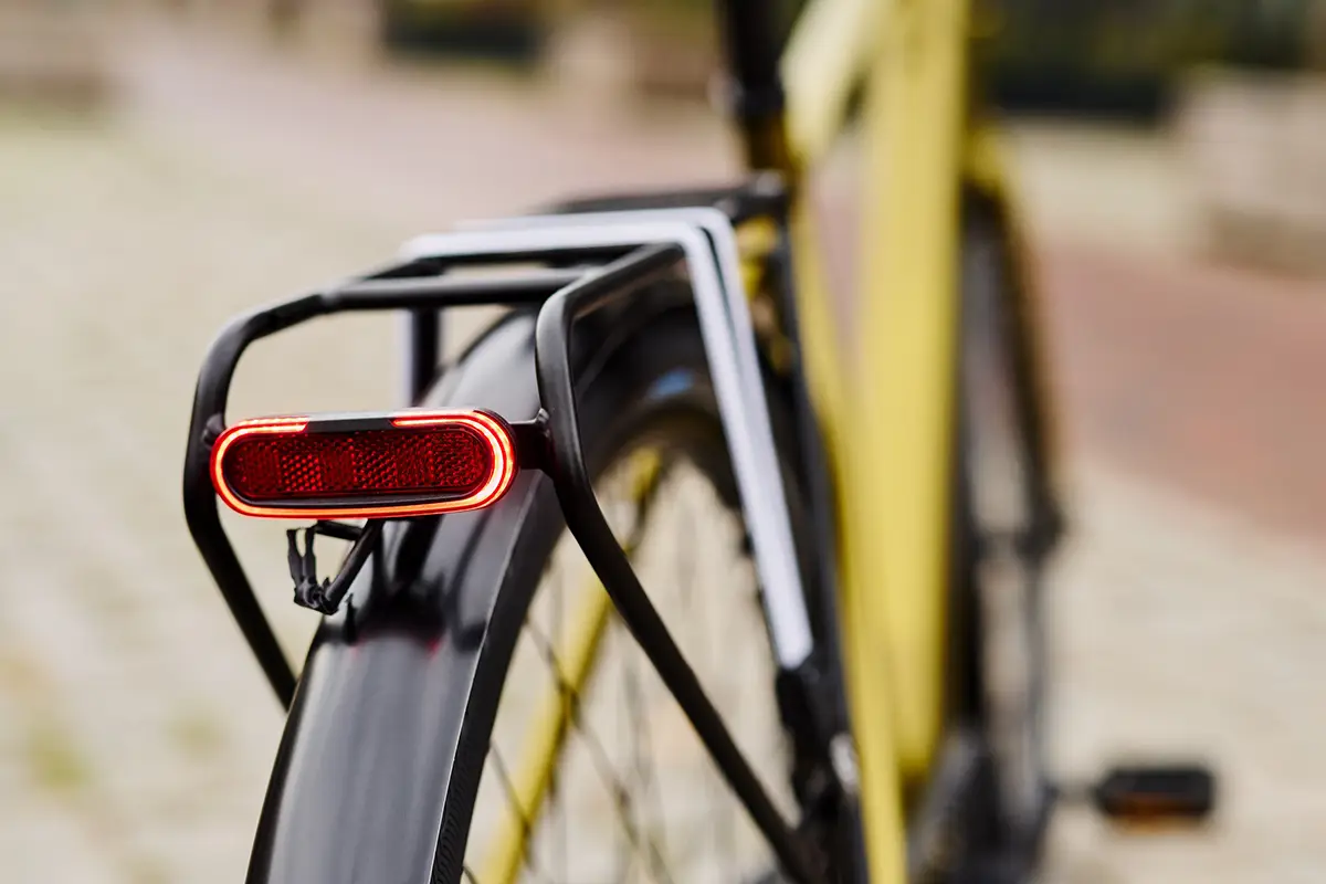 Detailansicht des elegant in den hinteren Gepäckträger und das Schutzblech integrierten roten LED-Rücklichts des E-Bikes.